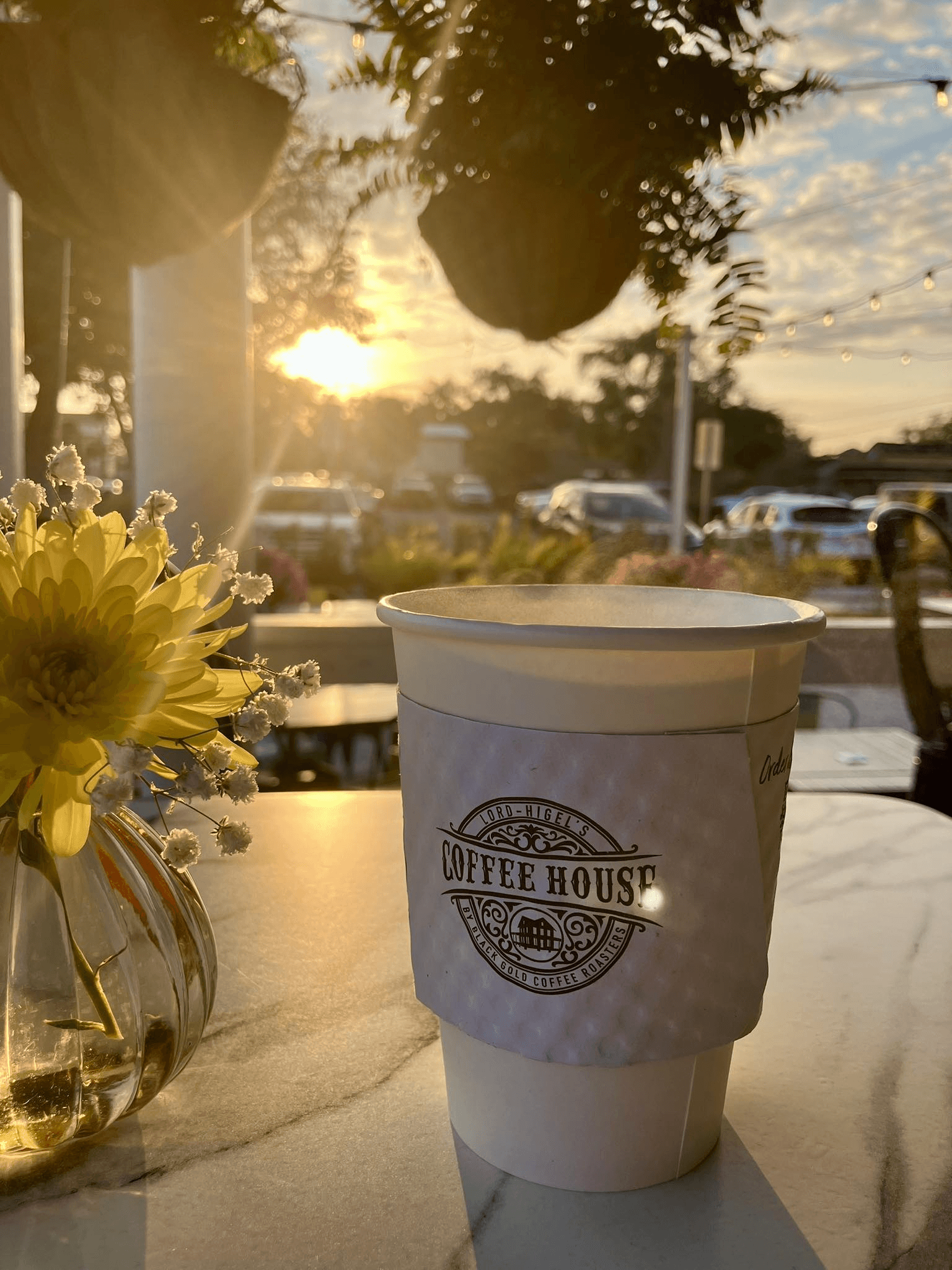 A cup of coffee on a porch table at sunset